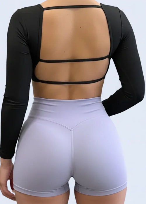 Person taking a mirror selfie in a gym wearing a black top and light purple leggings.