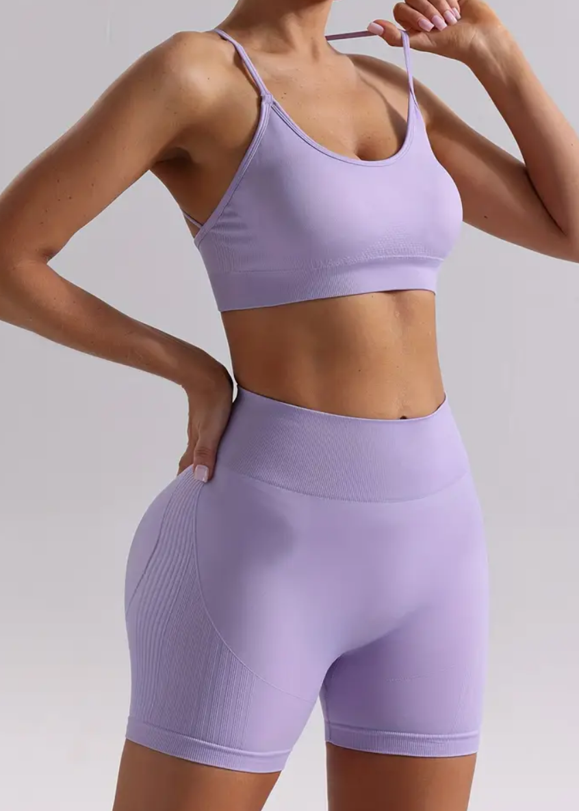 Person wearing a light purple sports bra and shorts on a plain background