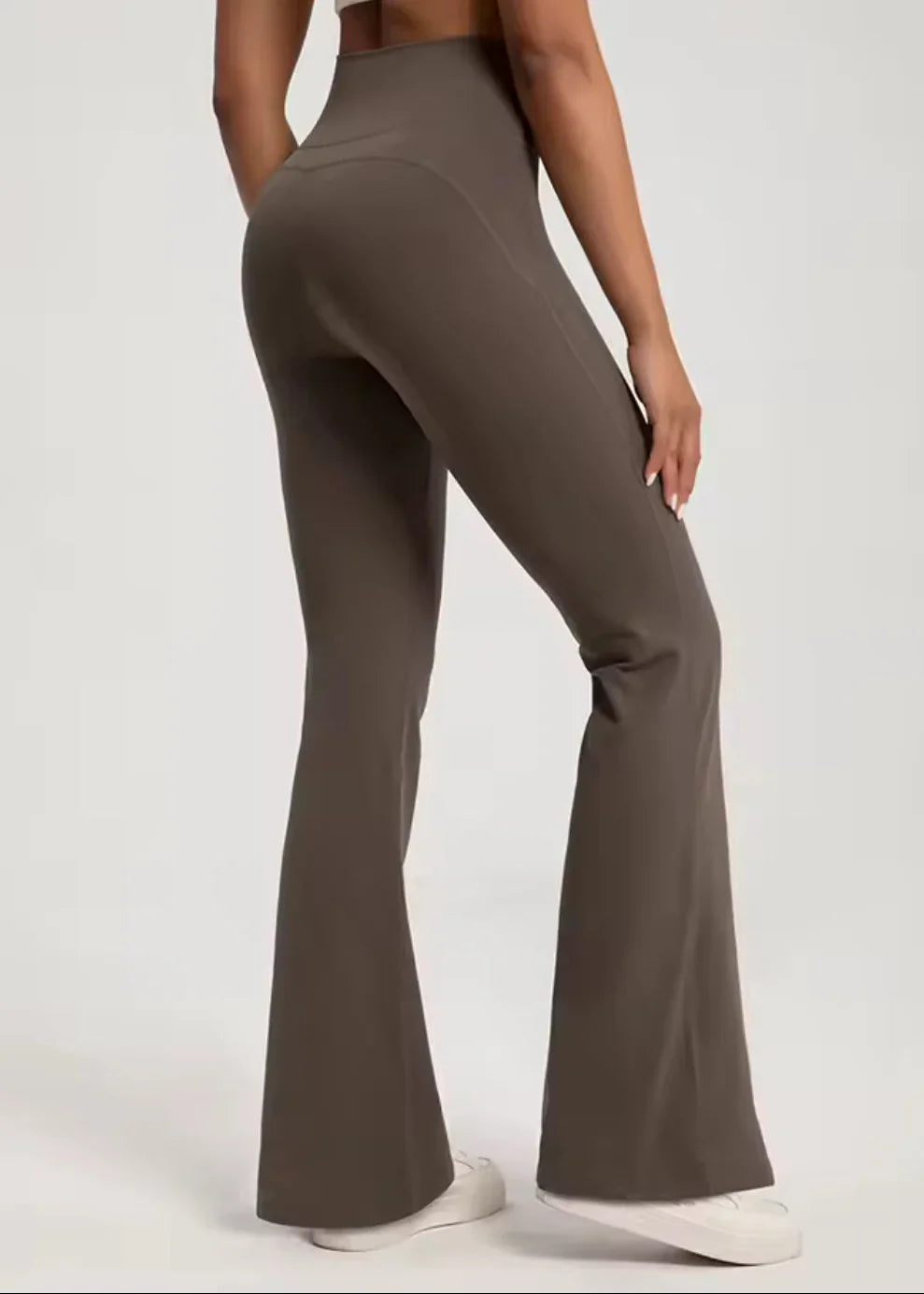 Woman modeling high-waisted brown flared activewear pants from GymDeity