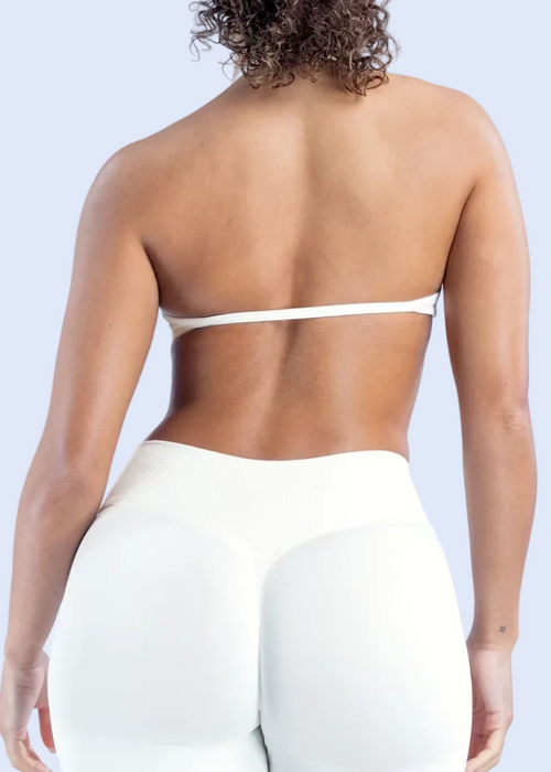 Person wearing a white strapless top and pants on a light gray background