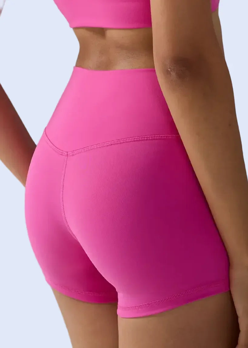 Person wearing bright pink athletic shorts on a plain background