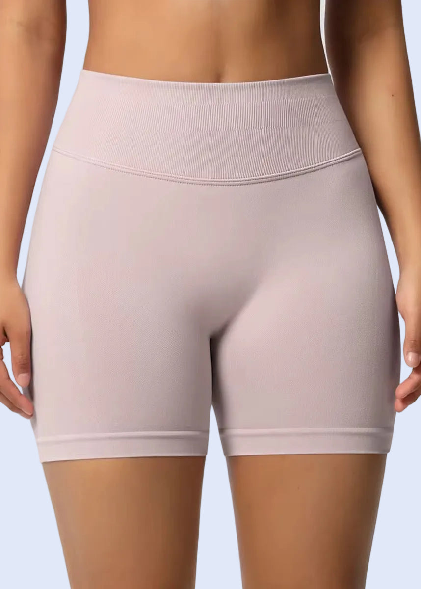 Light pink high-waisted shorts worn by a person on a plain background