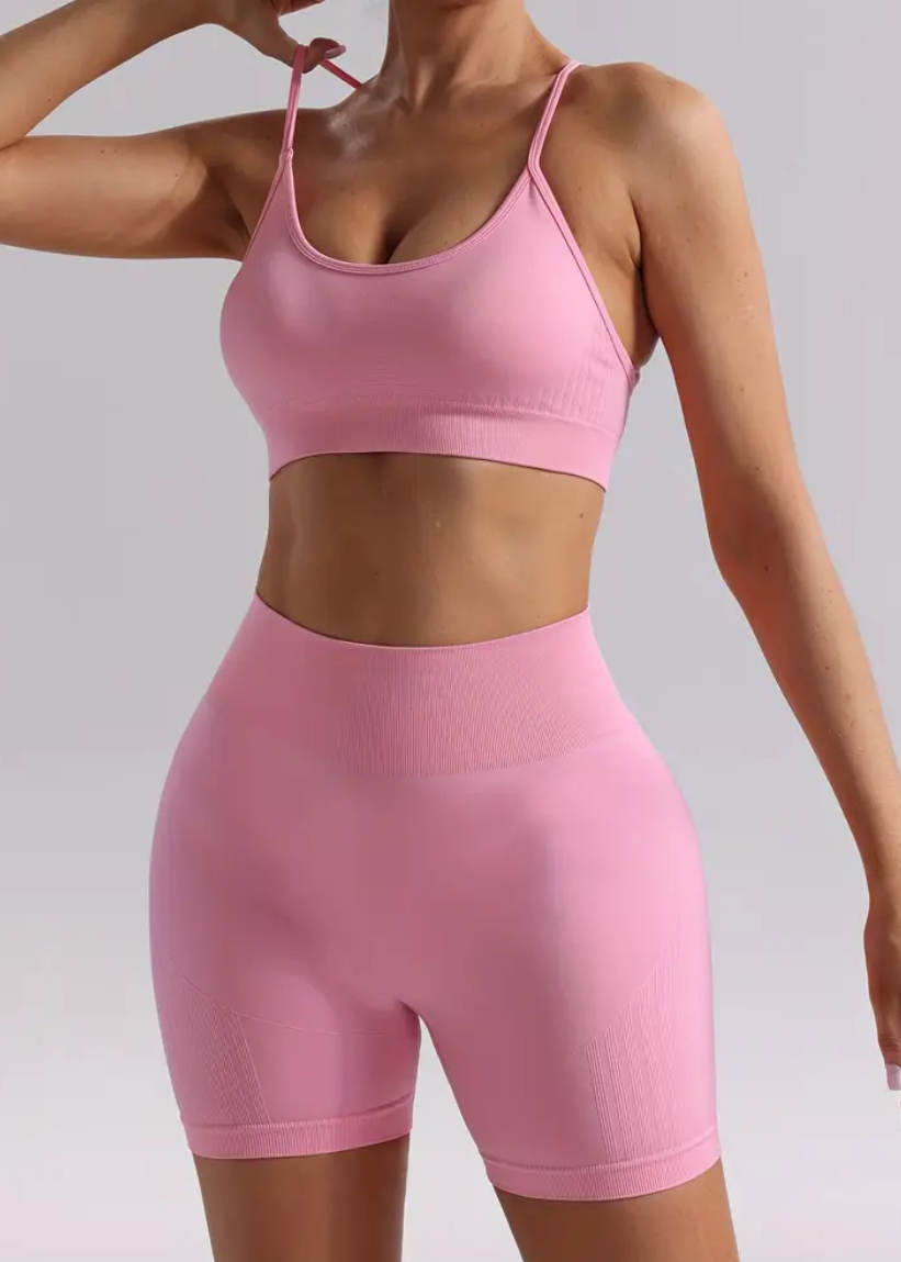 Person wearing a pink sports bra and shorts on a plain background