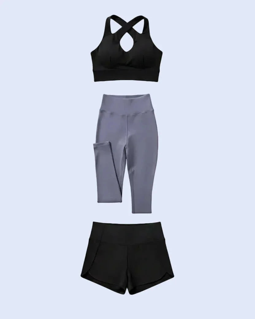 Woman taking a mirror selfie wearing a black sports bra and purple leggings.