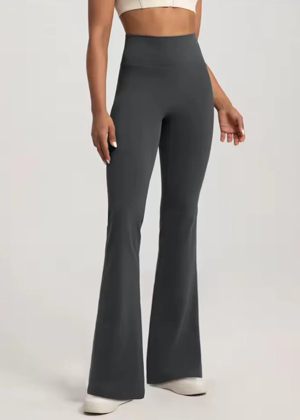 Woman modeling high-waisted black flared activewear pants from GymDeity