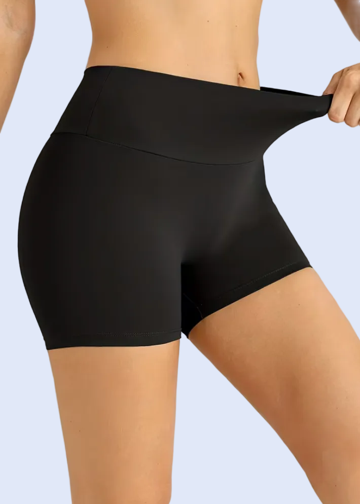 Person wearing black shorts on a plain background