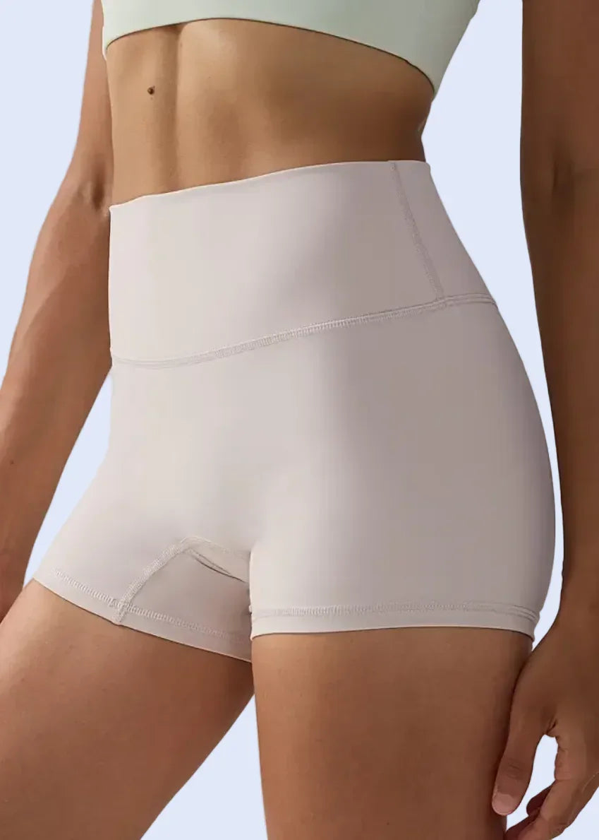 Person wearing beige shapewear shorts on a plain background