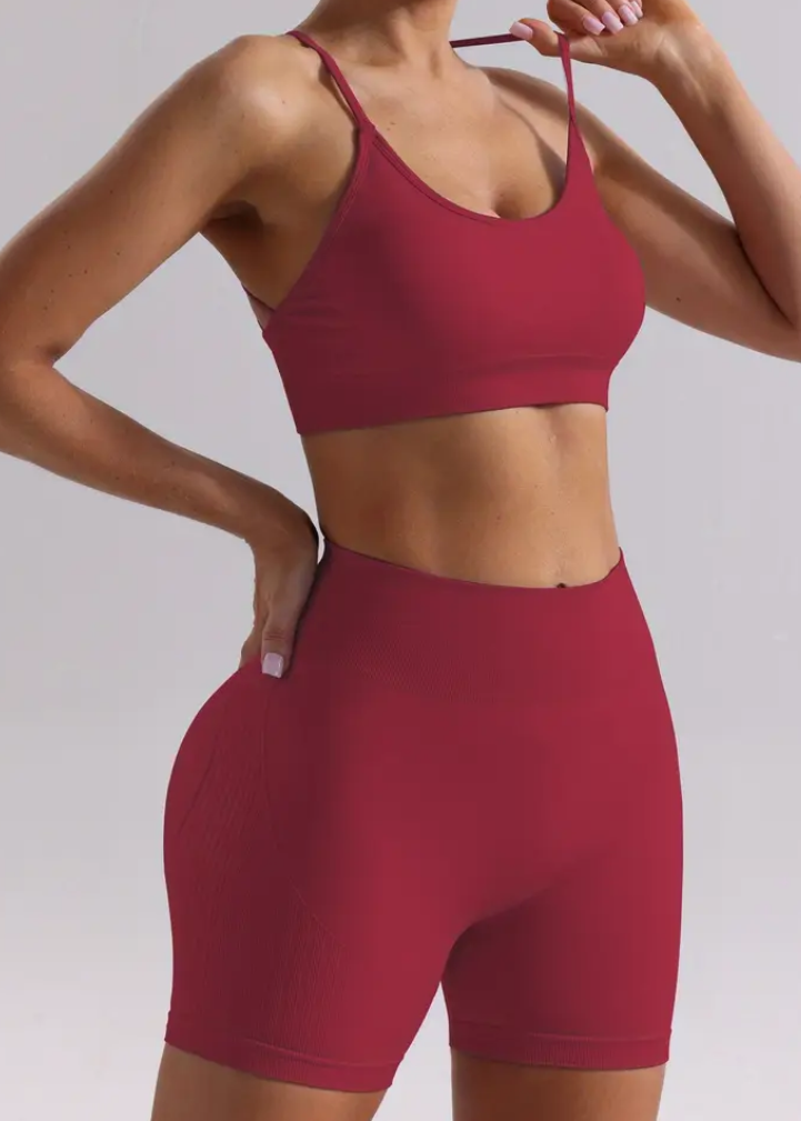 Person wearing a red sports bra and shorts on a plain background