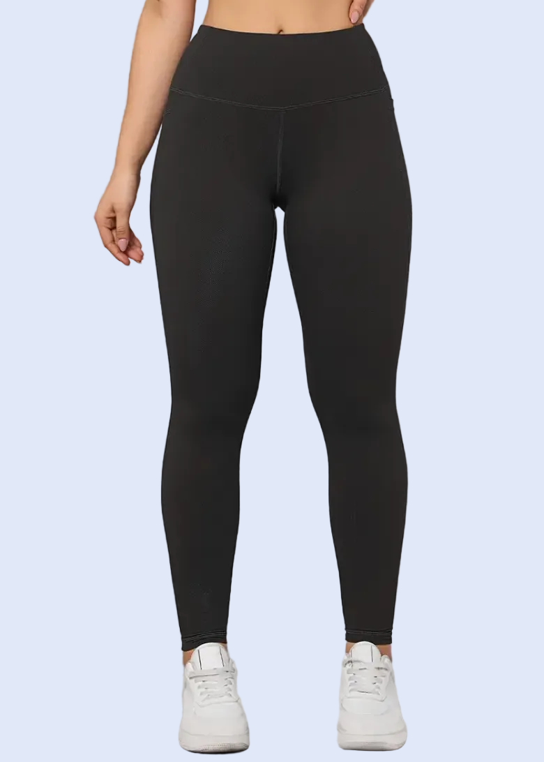 Person wearing black leggings standing against a light gray wall.