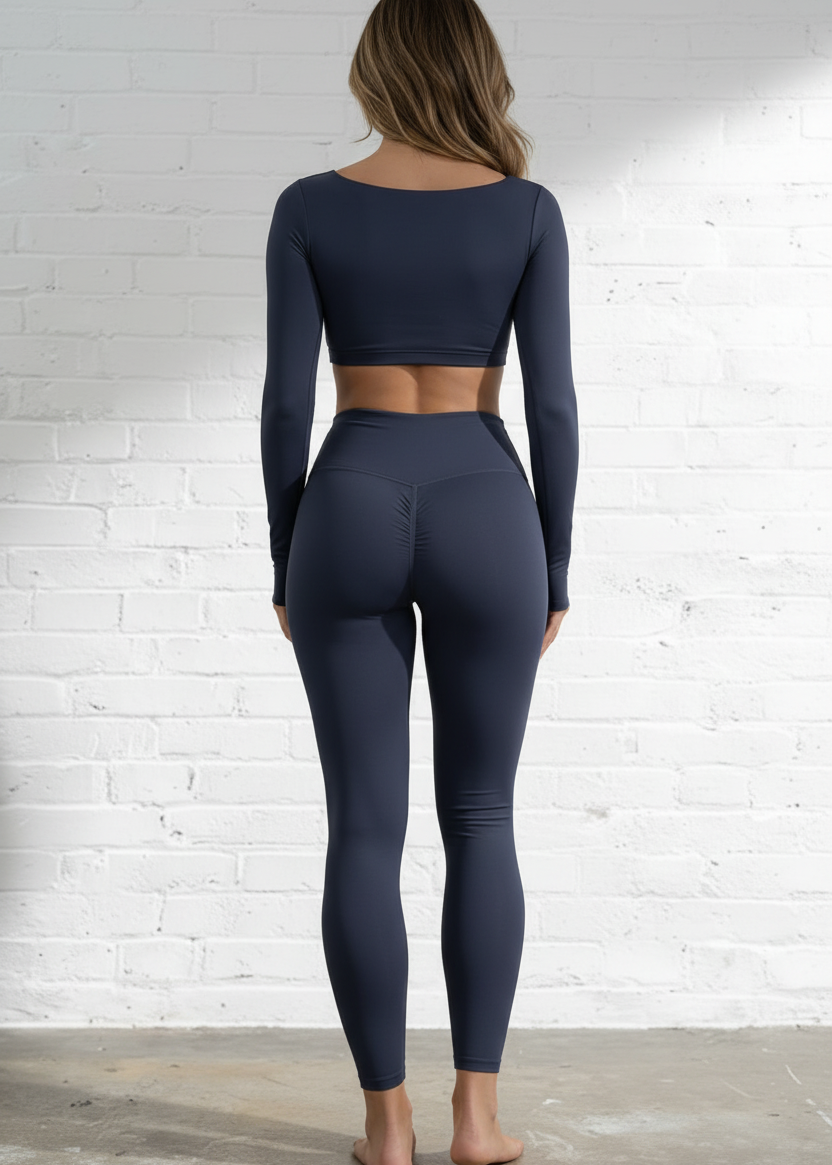 Person wearing a navy blue athletic outfit against a white brick wall.