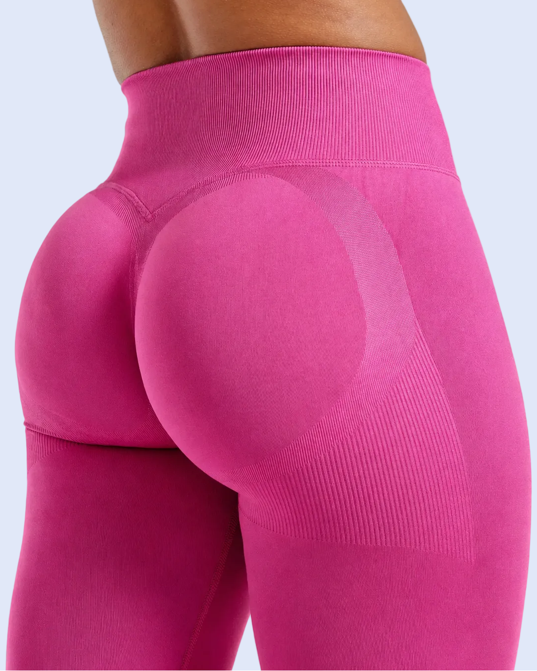 Close-up rear view of a person wearing bright pink high-waisted compression leggings with textured paneling on a light gray studio background.