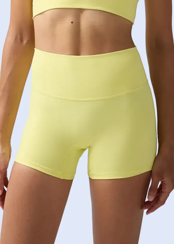 Person wearing yellow athletic shorts on a plain background