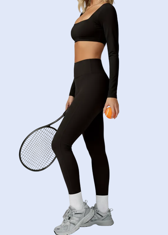 Person in black athletic wear holding a paddle and ball on a plain background