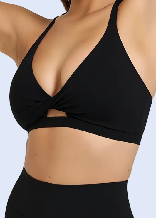 Woman wearing a black sports bra and leggings on a plain background
