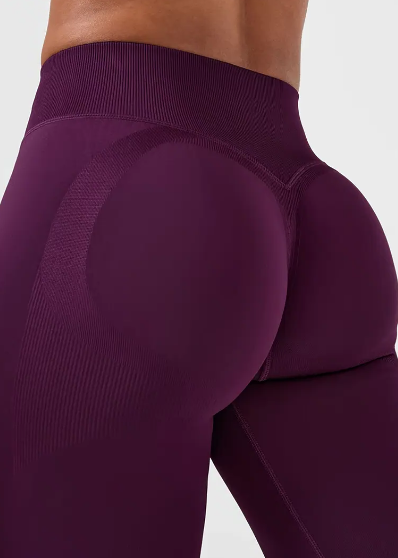 Close-up of a person wearing purple leggings on a plain background