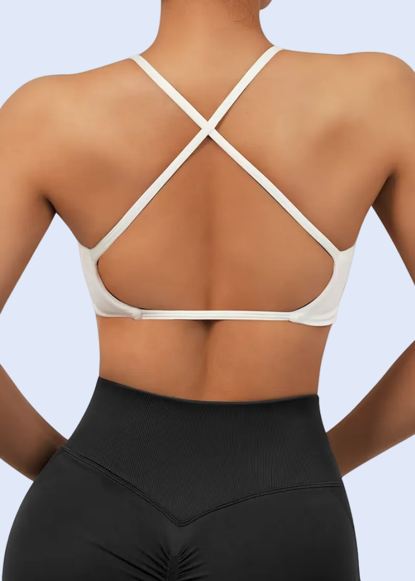 Person wearing a white sports bra and black leggings on a plain background