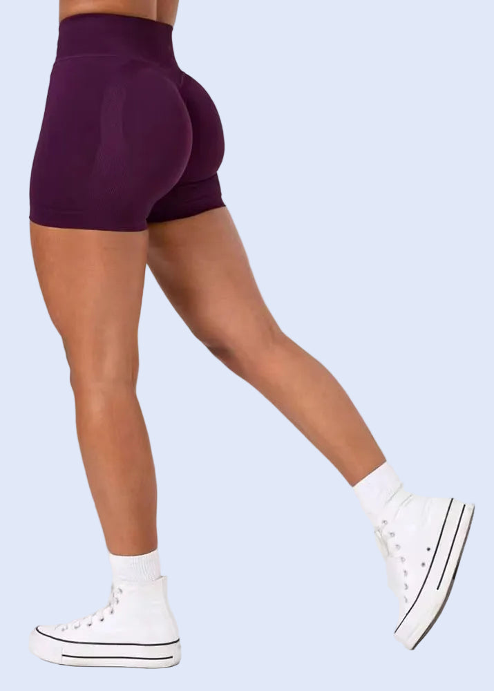 Person wearing purple shorts and white sneakers on a plain background