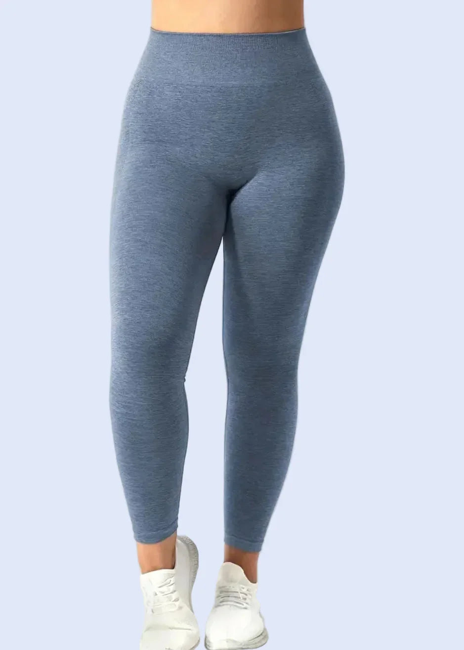 Woman wearing high-waisted blue seamless leggings and white sneakers, activewear style.