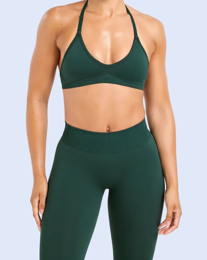 Woman wearing a green sports bra and leggings with a visible brand logo on a white background