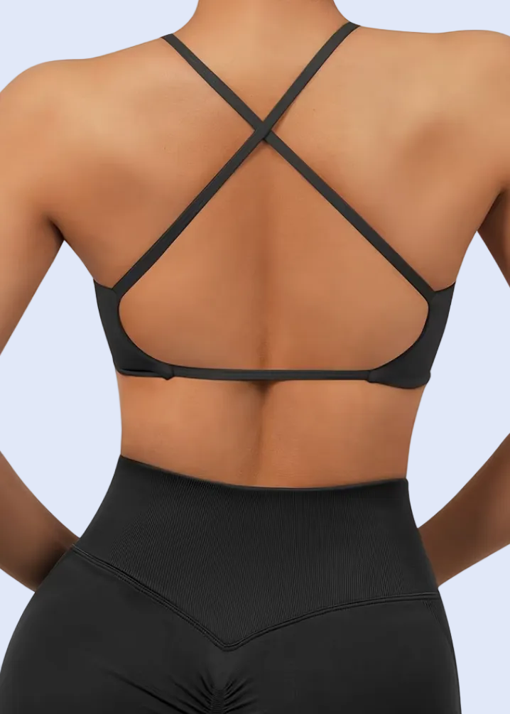 Black strappy top worn by a person on a plain background