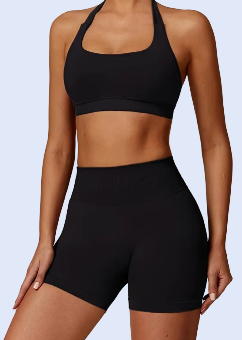 Person wearing a black sports bra and shorts on a gray background