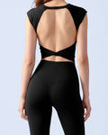 A woman shown from the back wearing a black athletic crop top with a large open back design and matching black high-waisted leggings, against a light gray studio background.