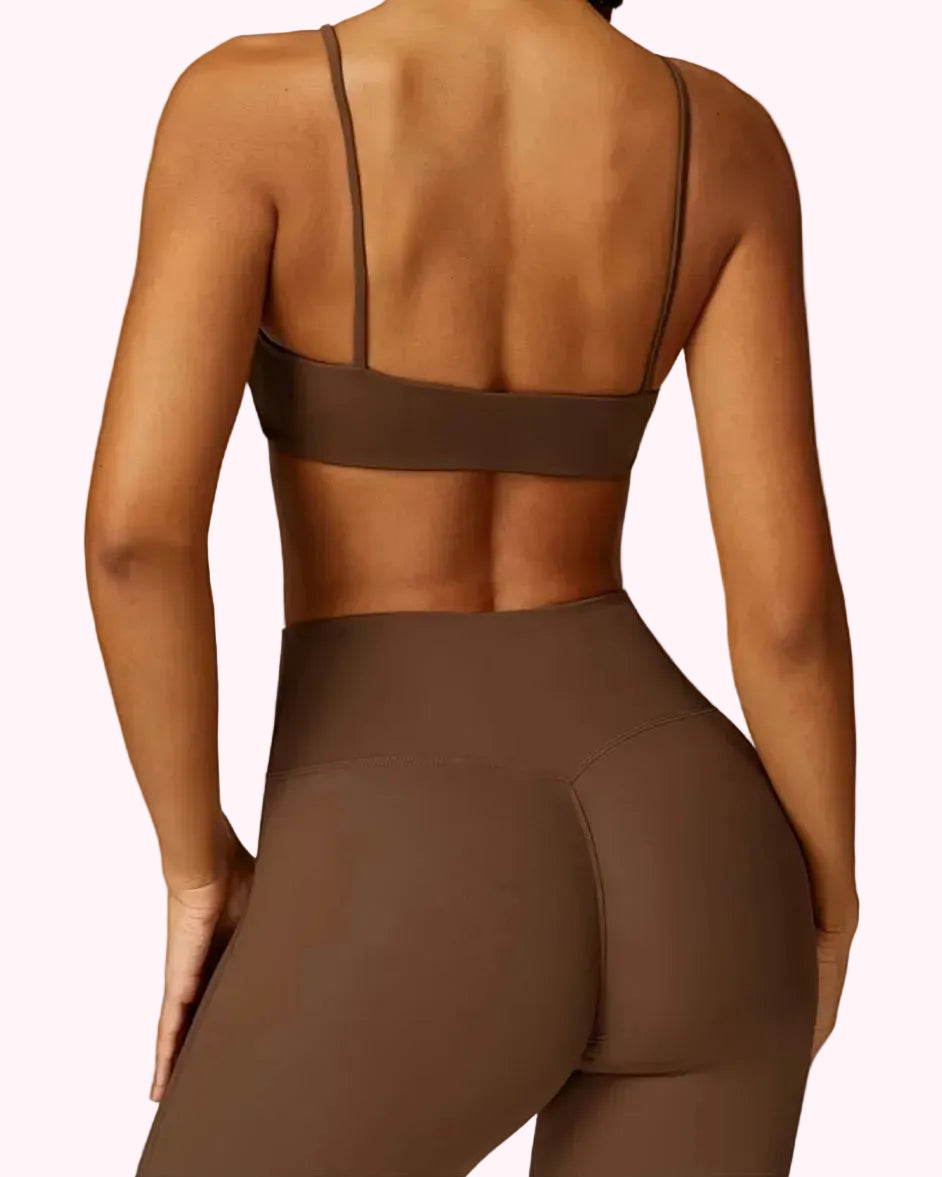 Person wearing a brown sports bra and leggings on a plain background