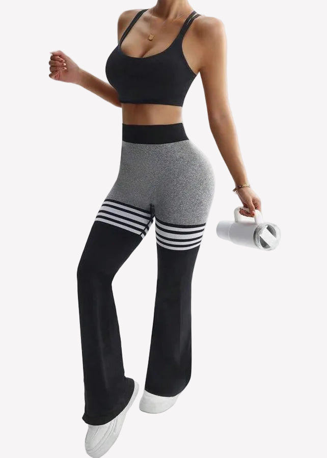 Person wearing a black sports bra and gray leggings with white stripes on a white background