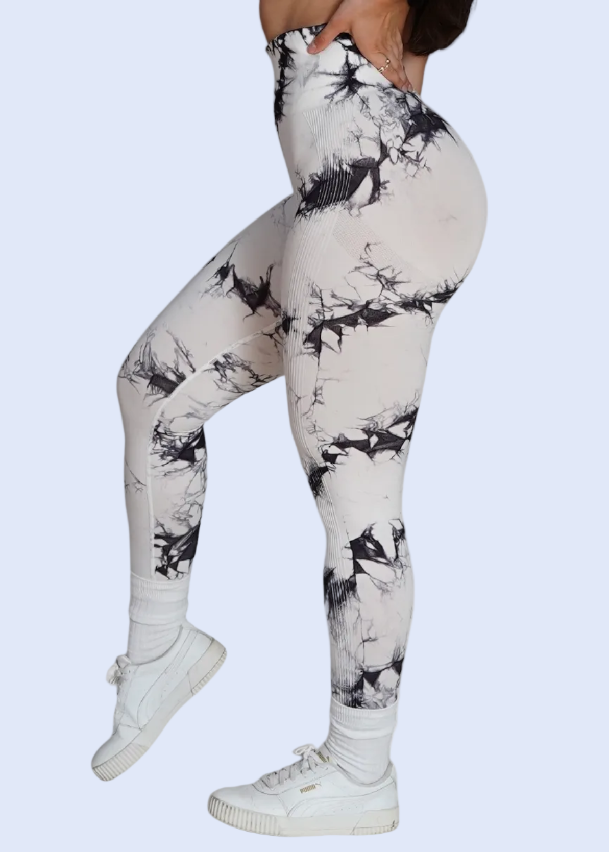 Person wearing white leggings with black abstract pattern on a white background