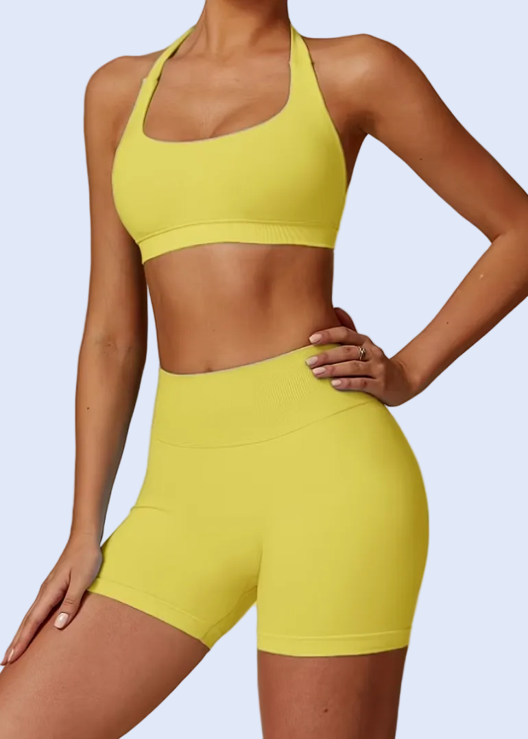 Person wearing a yellow sports bra and shorts set on a plain background