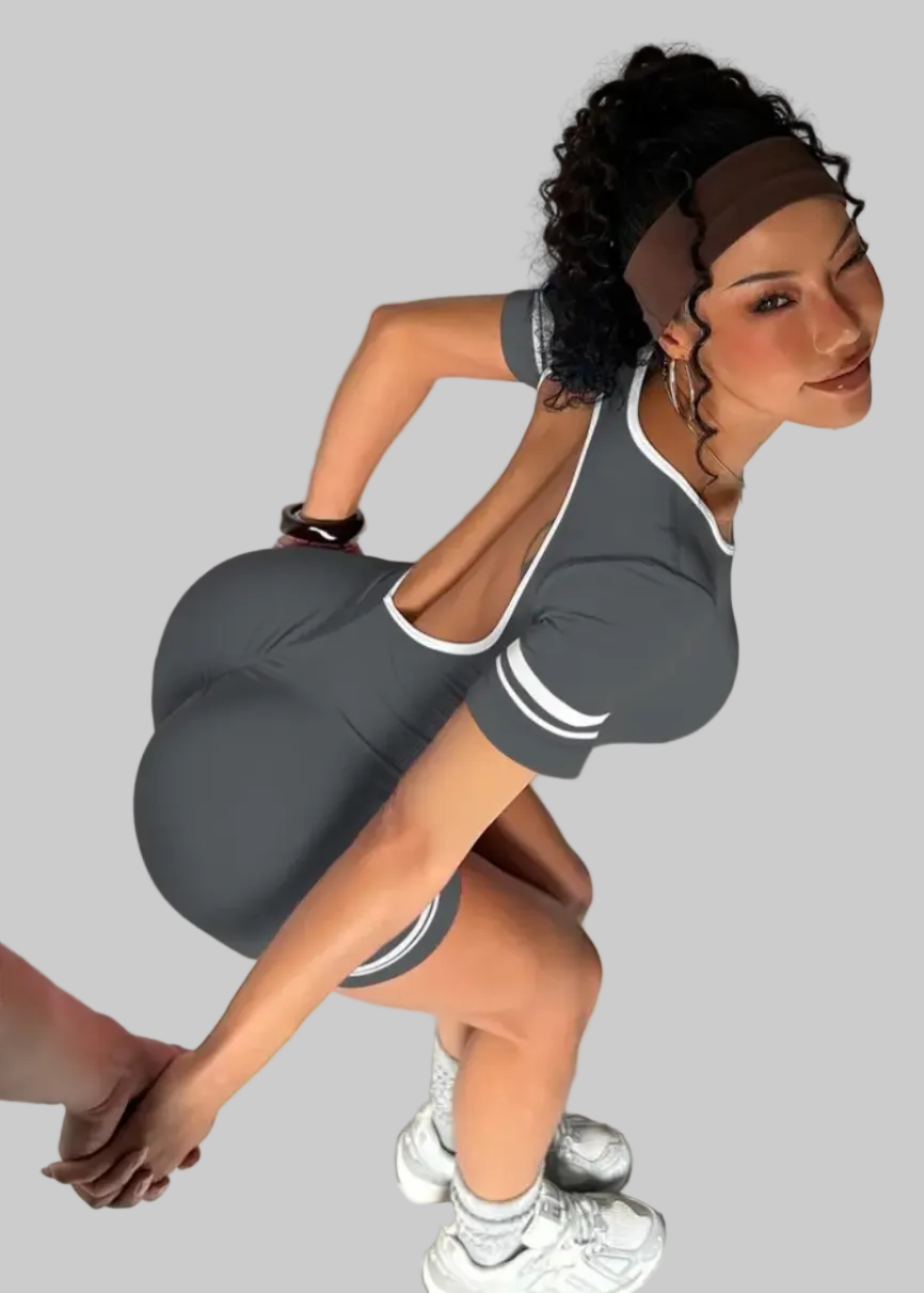 Woman in a gray athletic outfit posing against a plain background