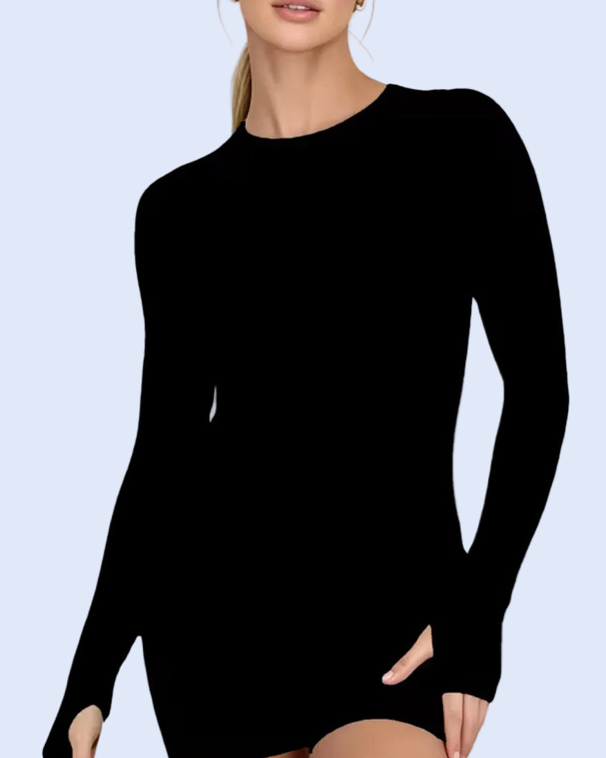 A woman wearing a black long-sleeve mini dress with a crew neck, shown from the lips down against a plain light background.