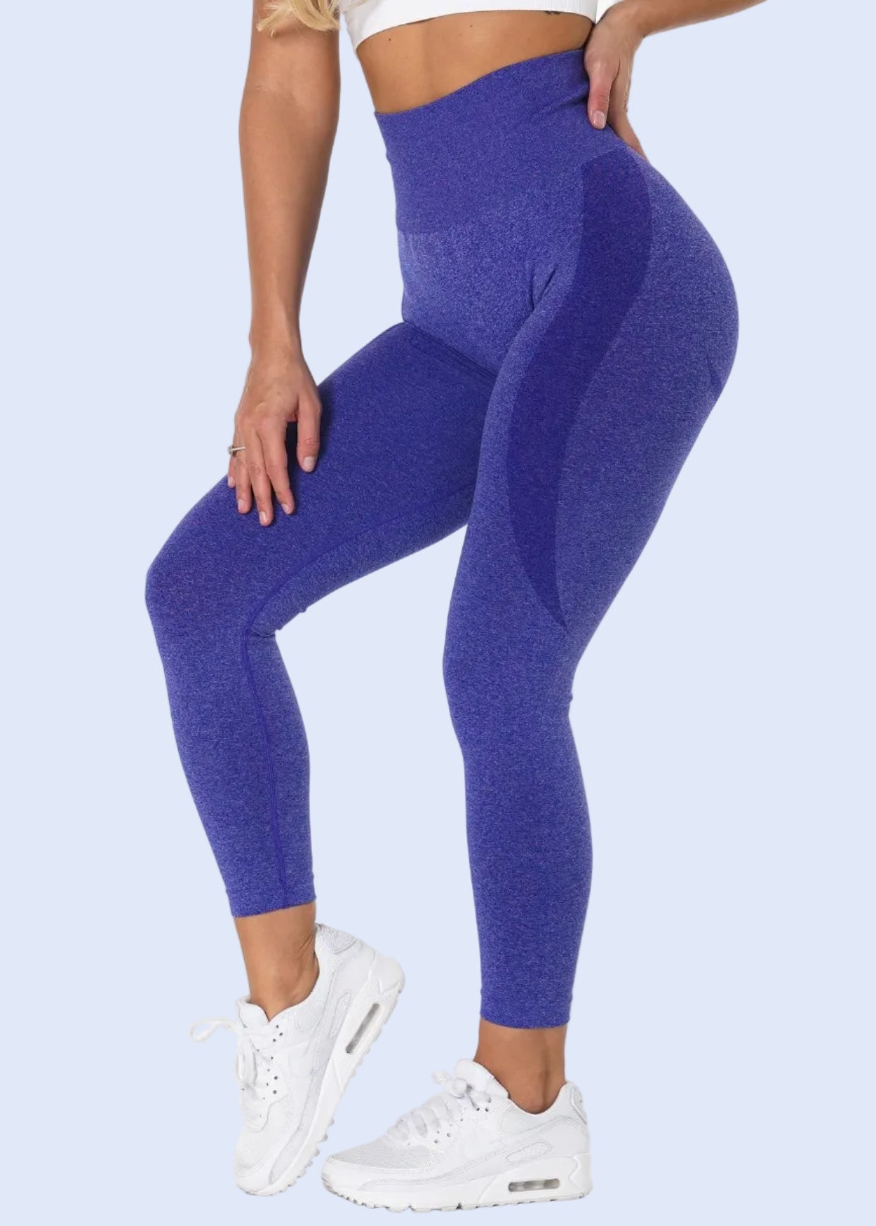 Person wearing blue leggings and white sneakers on a white background