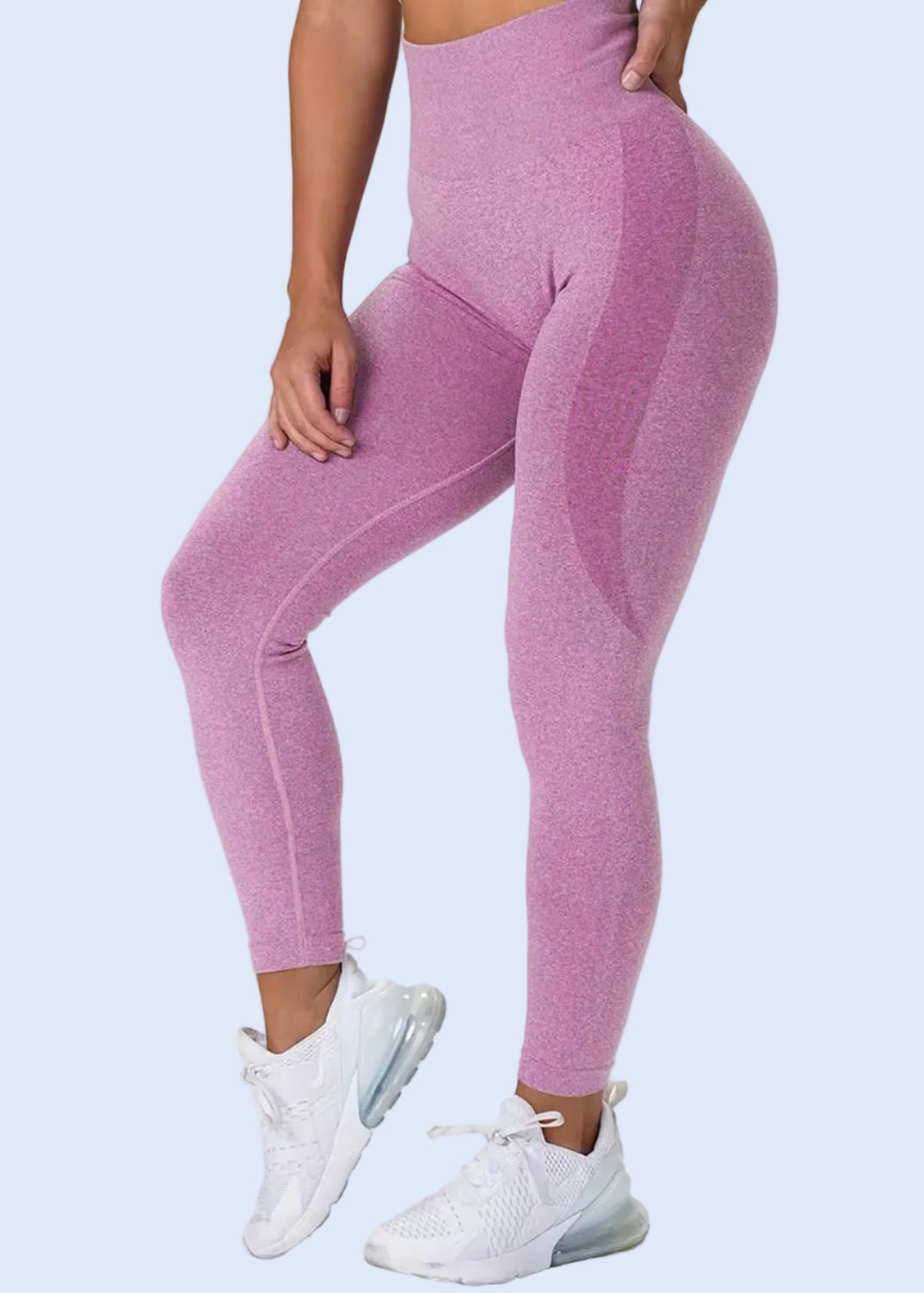 Person wearing pink leggings and white sneakers on a plain background