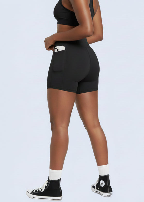 Person wearing black athletic shorts and sports bra with a plain background