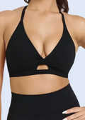 Woman wearing a black sports bra and leggings on a plain background