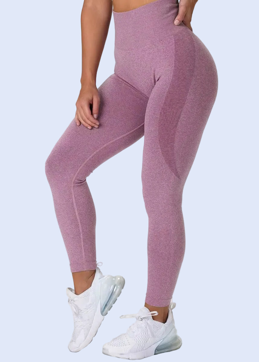 Person wearing pink leggings and white sneakers on a plain background