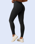 A person modeling high-waisted black leggings from the back, paired with white sneakers, against a light blue background.
