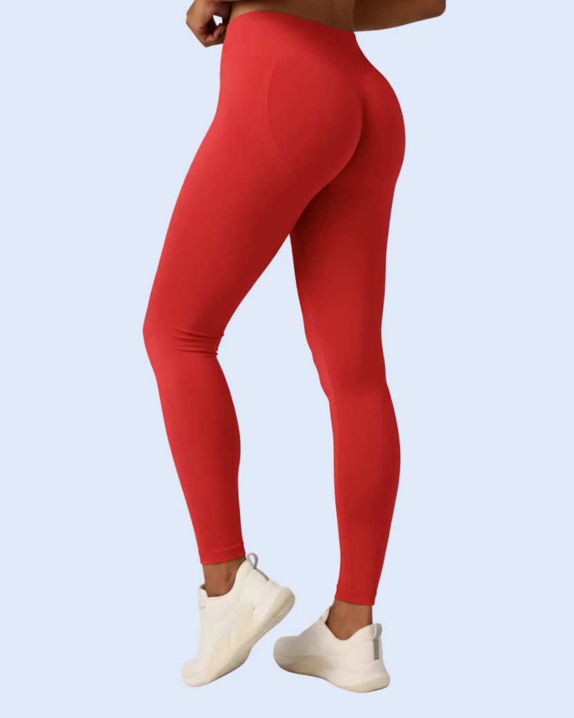 A person wearing bright red high-waisted leggings and white slip-on sneakers, shown from the back against a light blue studio background.