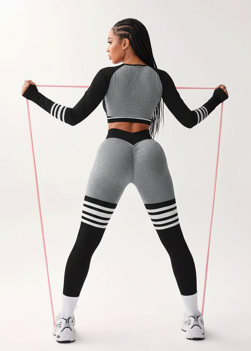 Woman in gray and black athletic wear with resistance bands on a white background