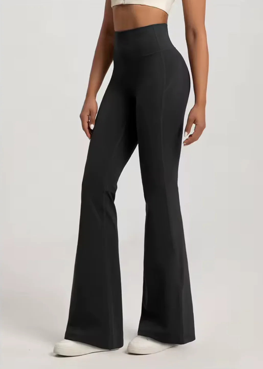Woman wearing high-waisted black flared activewear pants and white sneakers