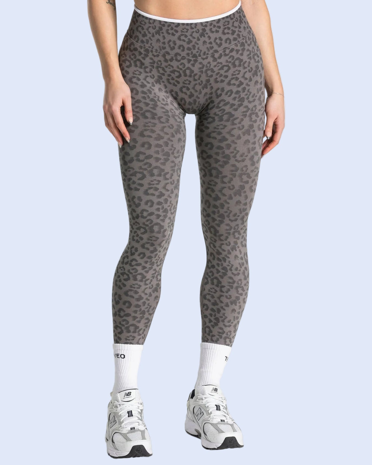 Person wearing gray leopard print leggings on a white background