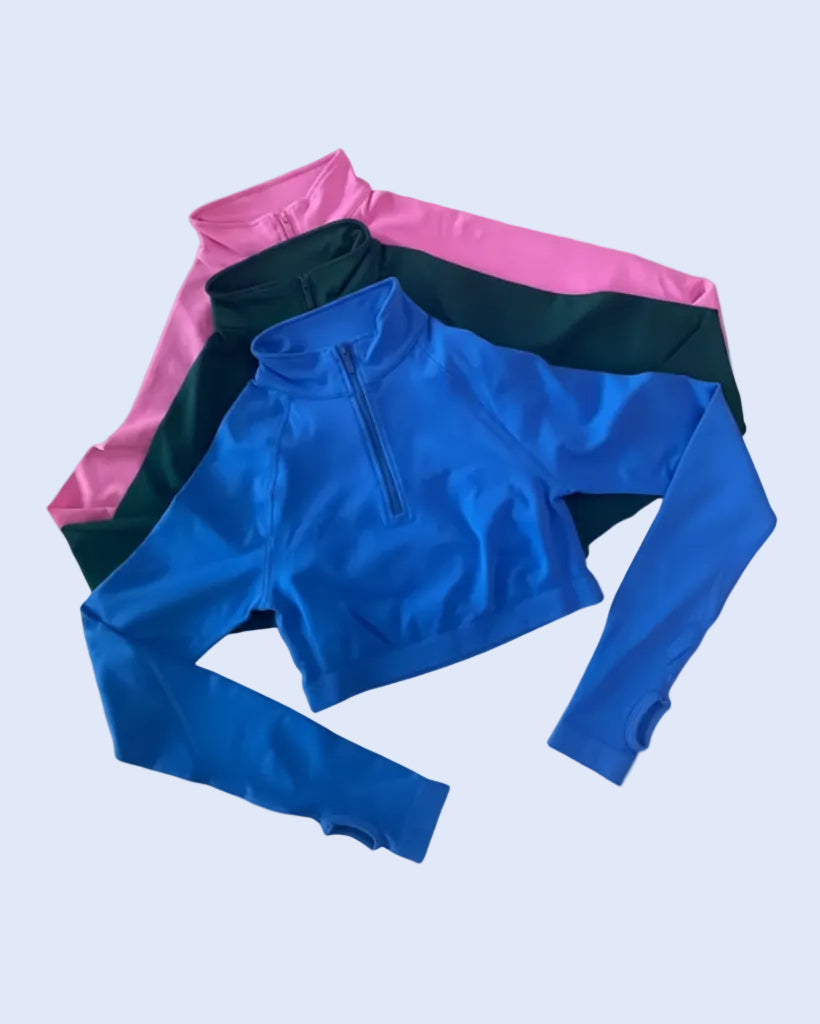 Three long-sleeve athletic quarter-zip pullovers in blue, dark green, and pink, arranged in a fan-like flat lay on a light gray background.