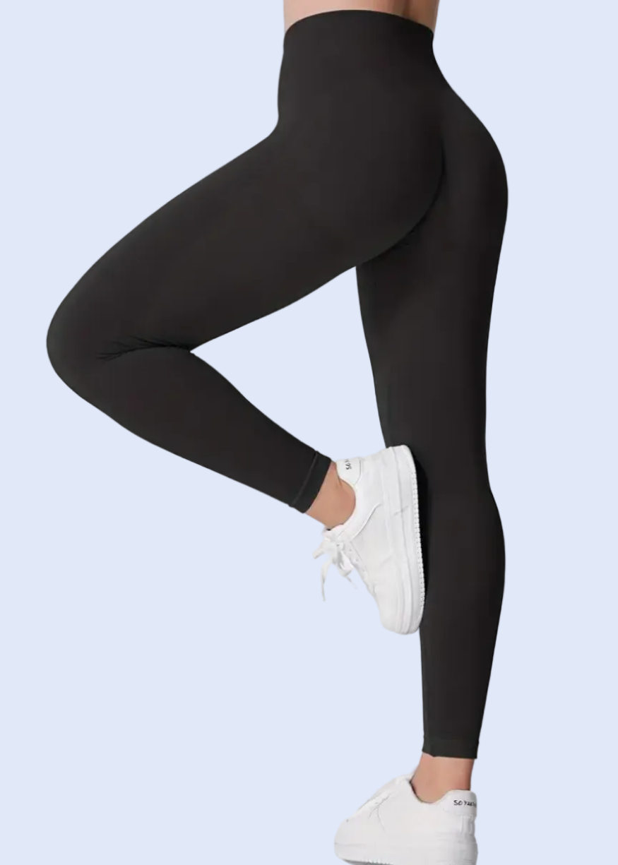 Person wearing black leggings and white sneakers on a white background
