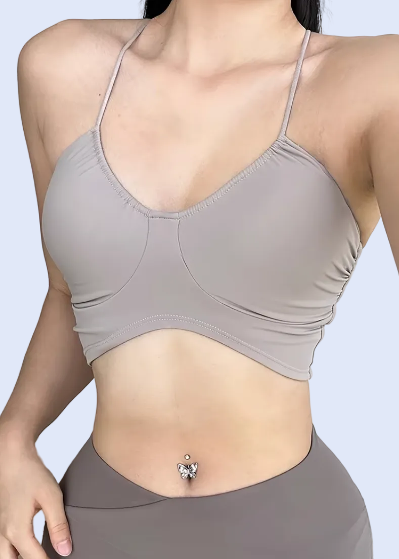 Person wearing a gray sports bra and leggings on a plain background