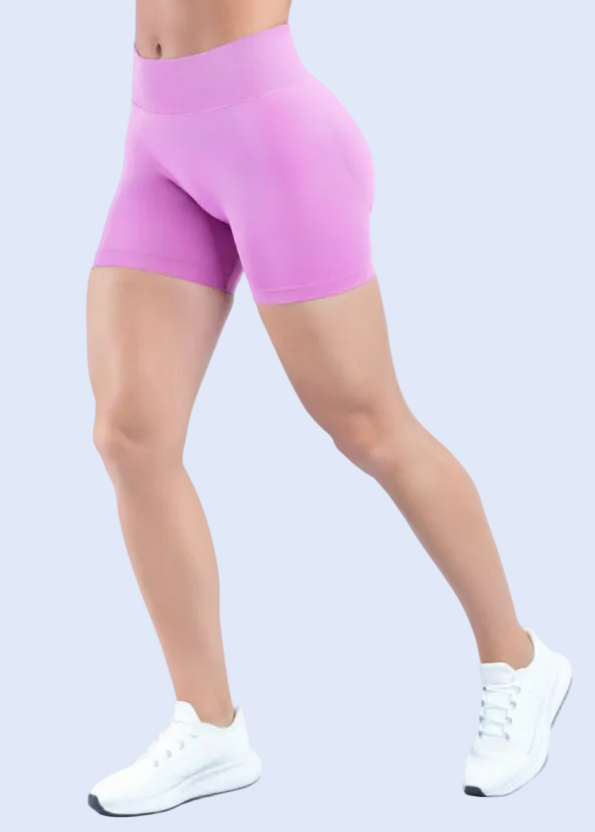 Person wearing pink athletic shorts and white sneakers on a light gray background