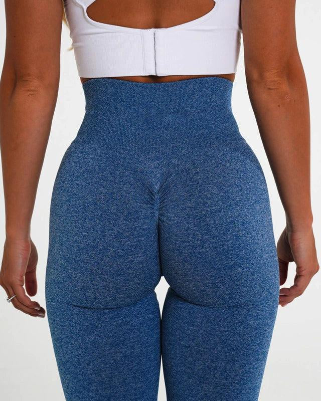 Person wearing blue leggings and a white top on a plain background