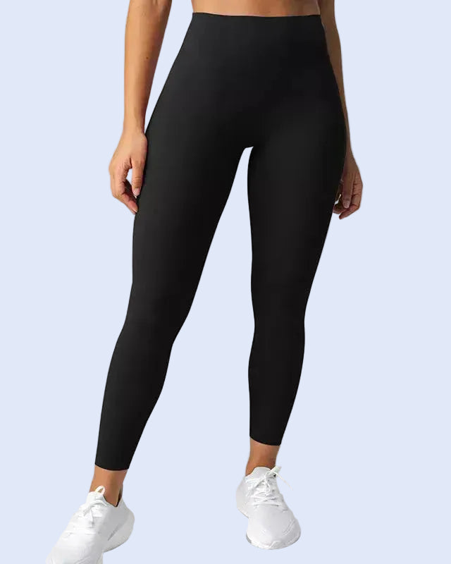 Person wearing black leggings on a plain background