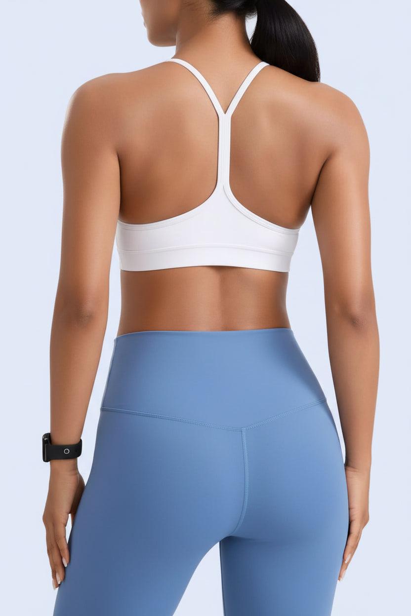 Person wearing a white sports bra and blue leggings on a gray background