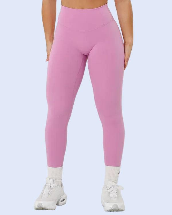 Person wearing pink leggings and sports bra on a white background